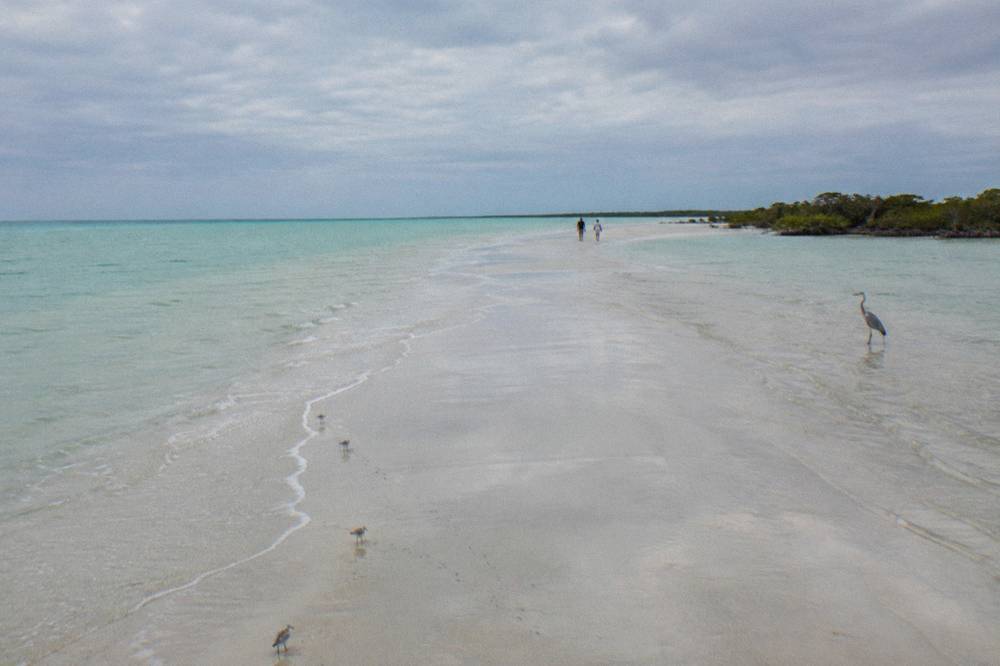 An empty stretch of shallow turquoise water and pale sand under a wide sky