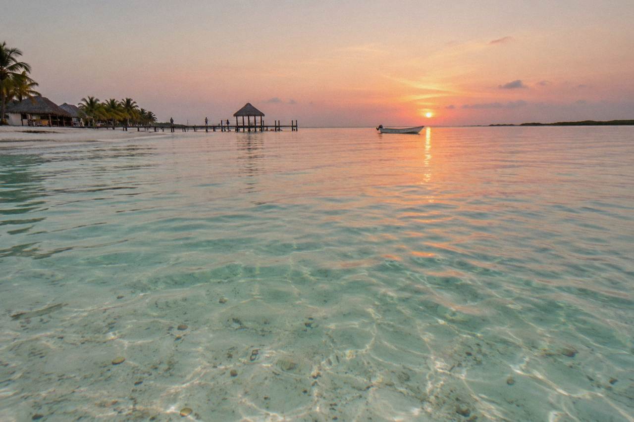 Calm turquoise water off Holbox with a small fishing boat on the horizon at sunrise