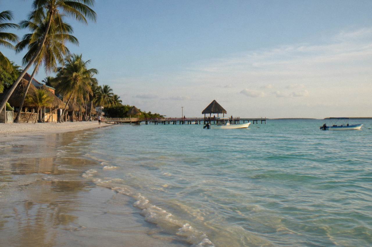 Calm shallow water off a sandy island beach under a wide morning sky