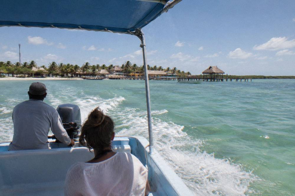 A small open boat crossing blue open water with a light chop under a clear sky