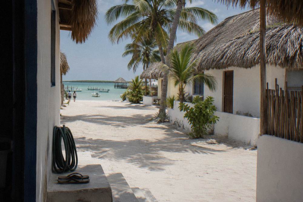 A quiet sandy street with palm trees and low beach buildings on a small car-free island