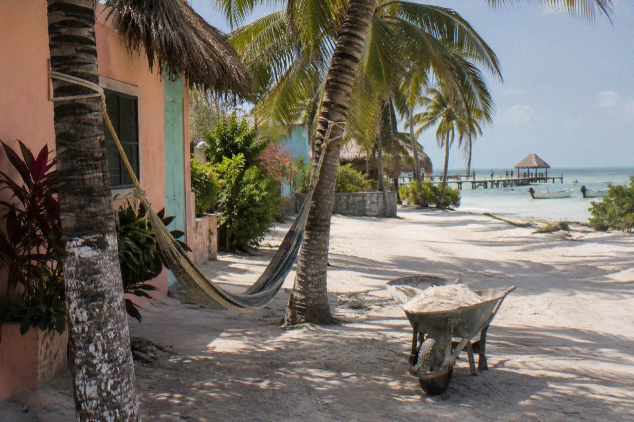 Sand street in Holbox village with pastel painted walls and hammocks strung between palms