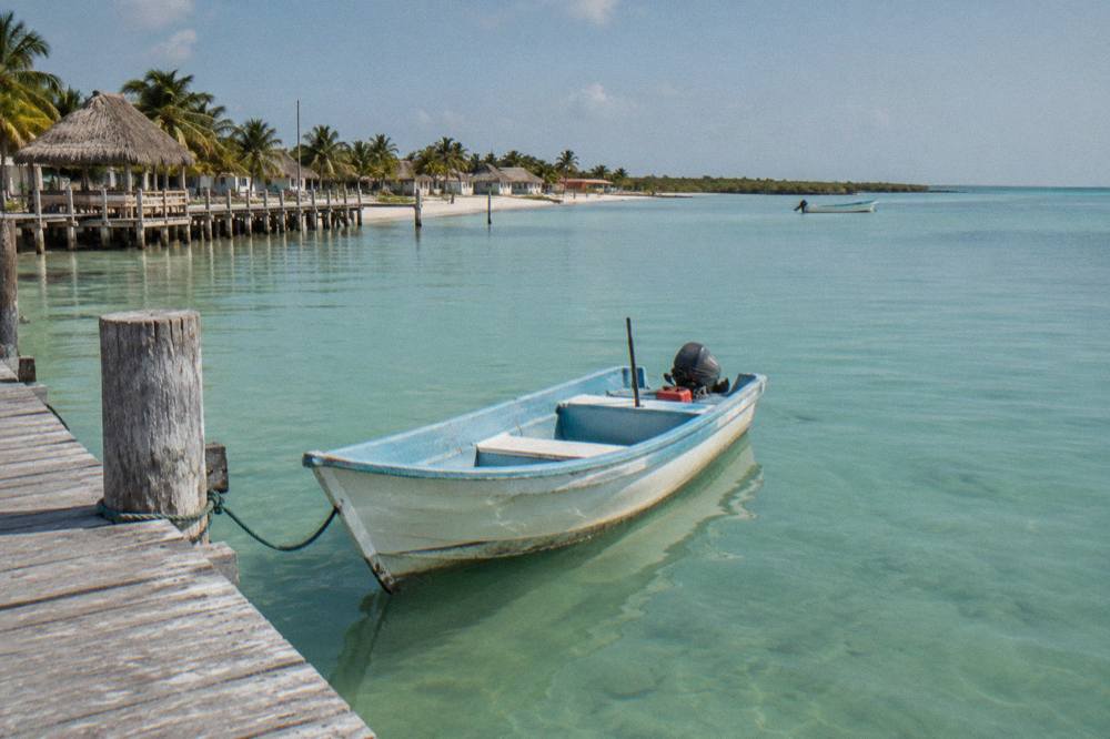 Small open boat moored at a wooden dock beside calm turquoise shallows