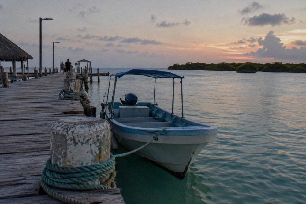 Wooden ferry pier with a small passenger boat at dusk beside calm water