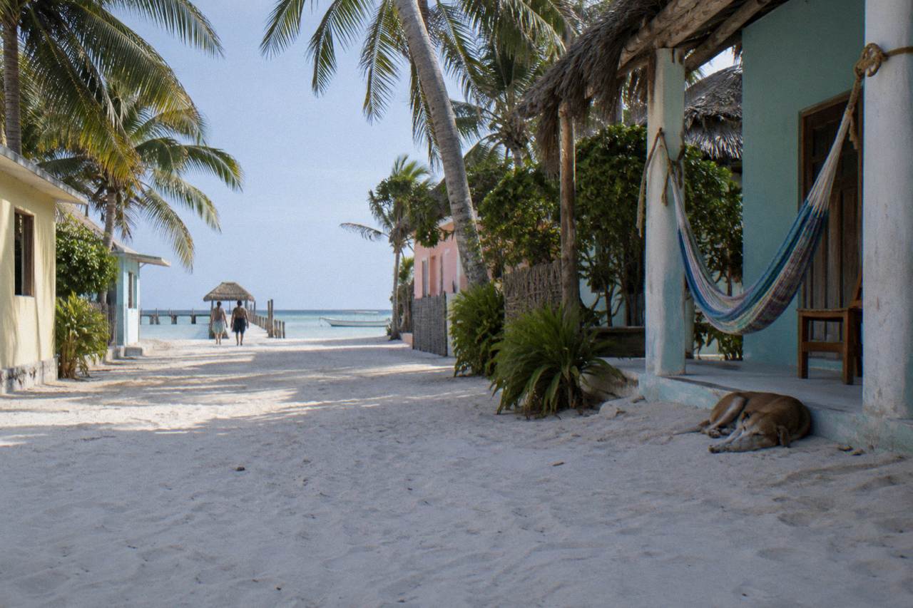 Quiet sandy street with pastel buildings and palm trees on a small island
