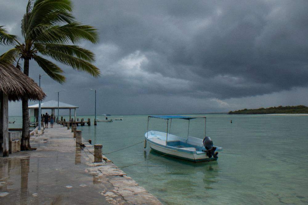 Dark storm clouds gathering over calm shallow water near an island coastline