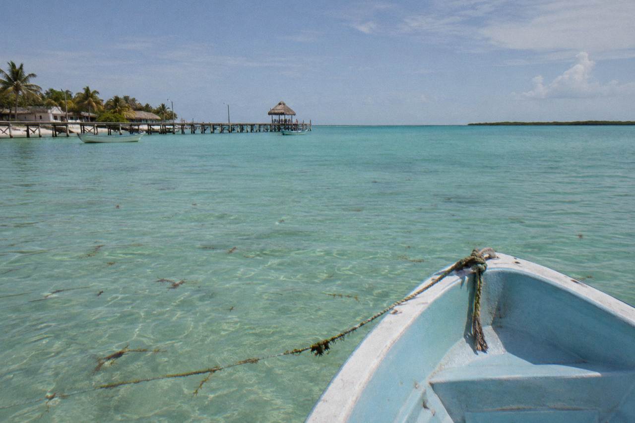 Empty turquoise water beyond the bow of a small boat off a tropical island shoreline