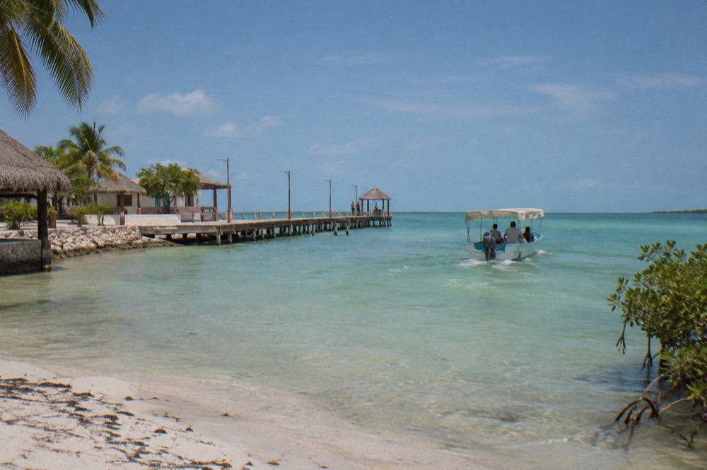 Small open boat with a canopy cruising across shallow green water toward open sea