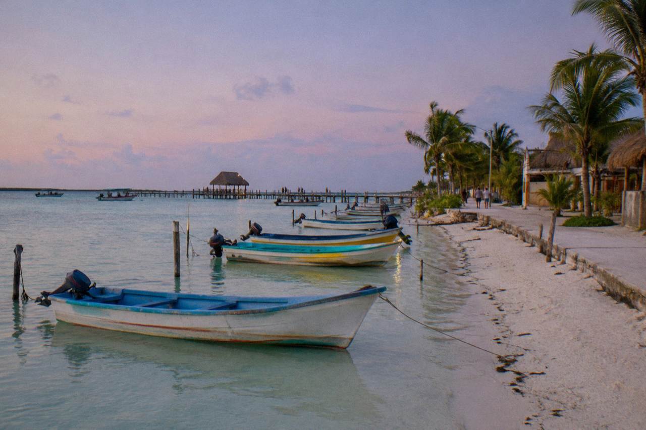 Colourful fishing boats moored along a calm waterfront street on a small island