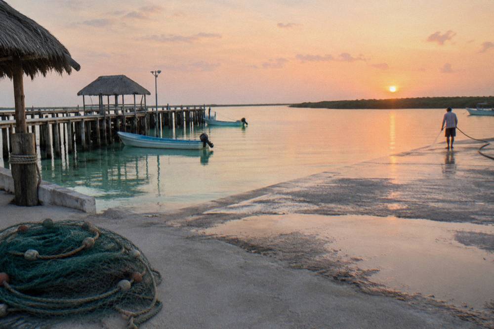 Sunrise over a shallow lagoon with a wooden pier and still water