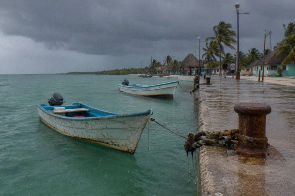 Wooden fishing boats moored at a Holbox dock under a grey afternoon sky