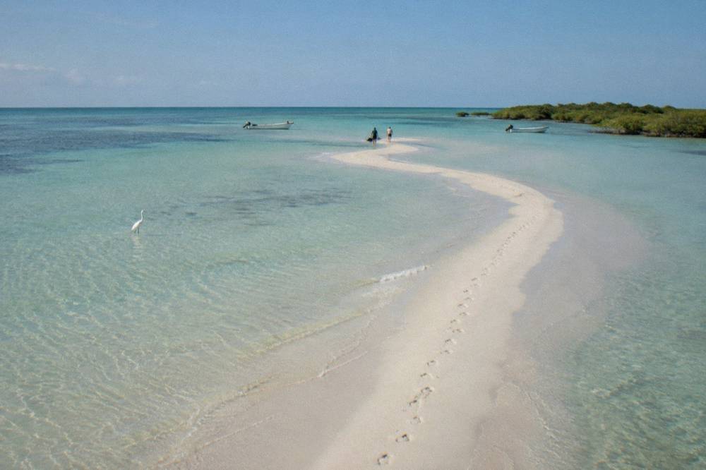 Empty white sandbar meeting calm shallow sea at Punta Mosquito on a clear morning