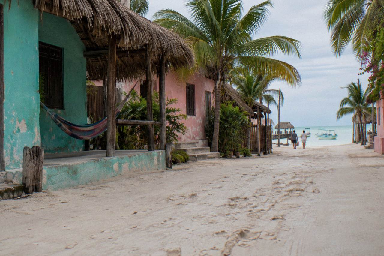 Wide sandy street in a small island village with painted walls and bicycles leaning against a fence