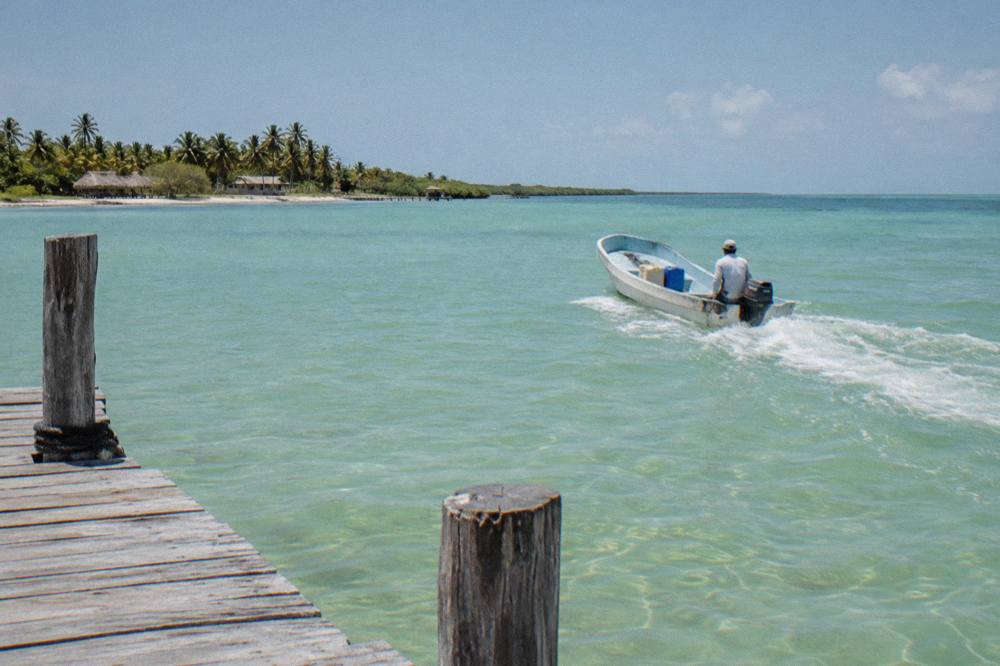 Small open boat crossing calm open water toward a distant shoreline