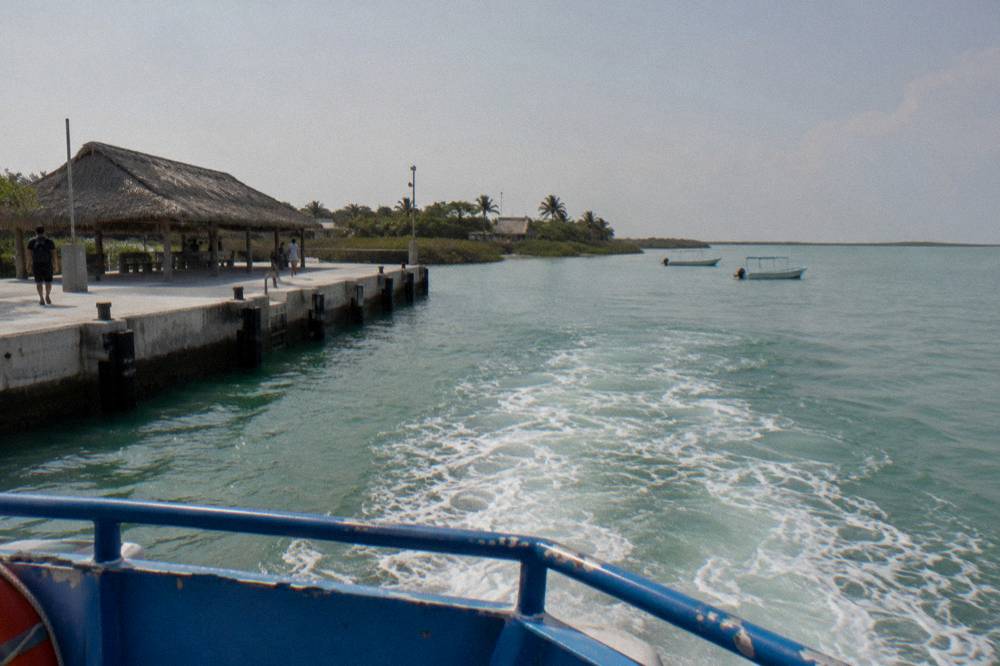Passenger ferry crossing a calm lagoon toward a small island shoreline
