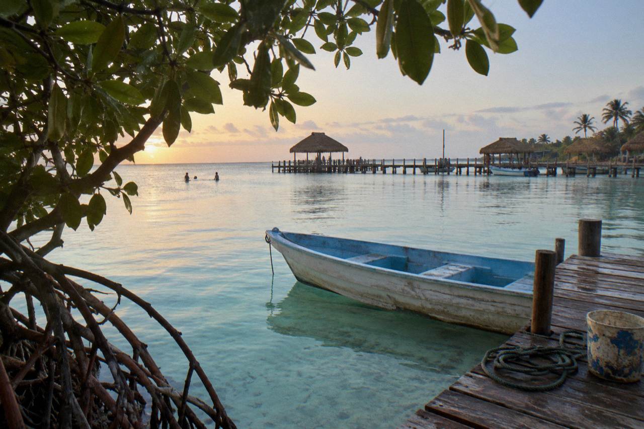 Small boat moored beside shallow turquoise water near mangroves on a calm morning