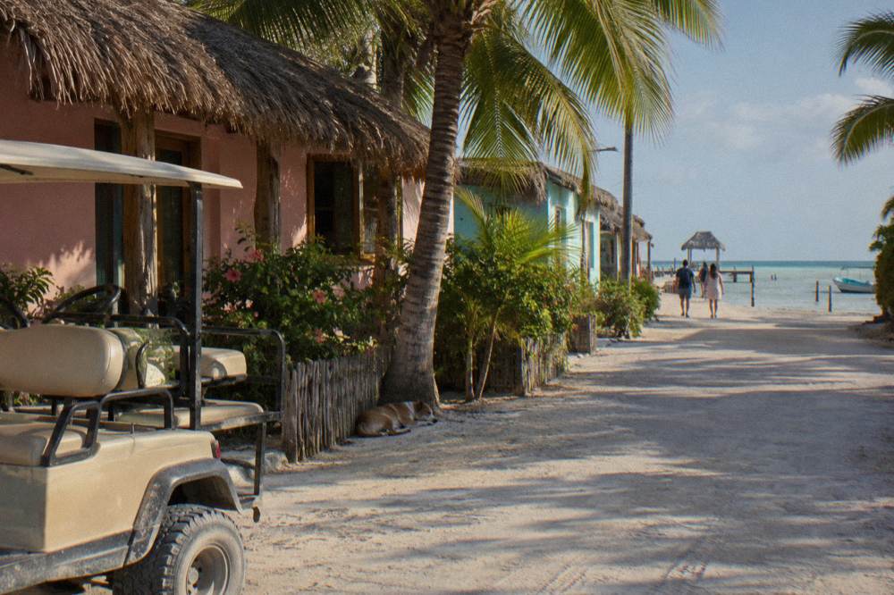 Golf cart parked on a sandy street beside pastel painted houses in Holbox