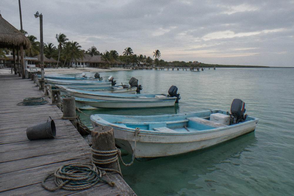Small fishing-style boats anchored in a line at a Holbox dock in early morning light
