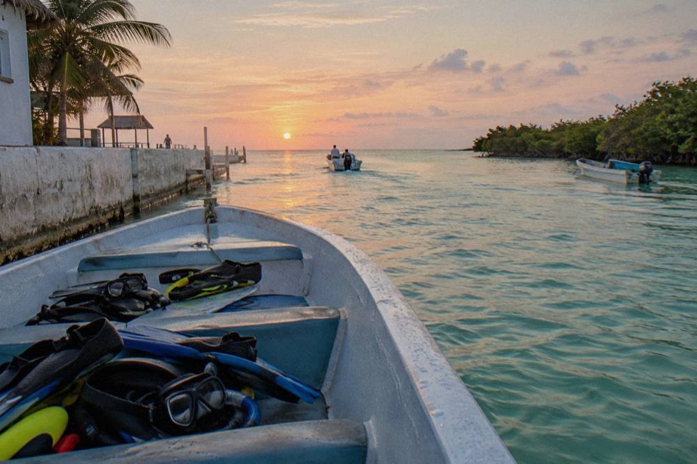 An open speedboat with snorkel gear on the seats heading out across calm open sea at sunrise