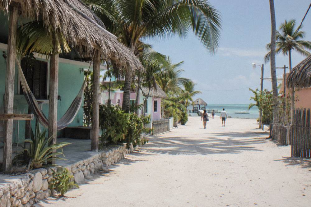 A quiet sandy street on a small car-free island with palm trees and pastel buildings