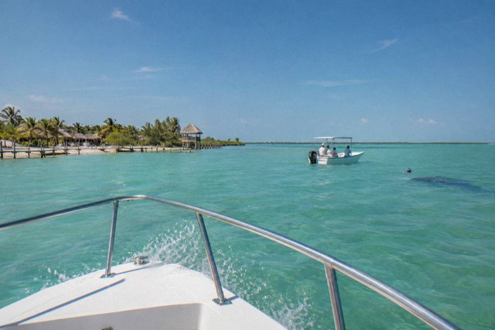 Open blue water horizon seen from the bow of a moving boat with spray at the rail