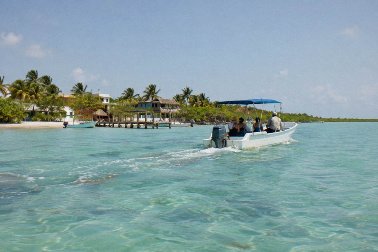 Small boat crossing open turquoise water near Isla Mujeres on a calm morning