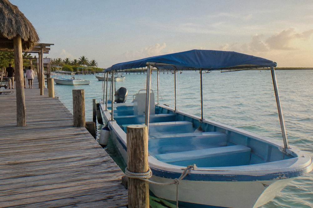 A covered boat anchored at a wooden marina dock in morning light