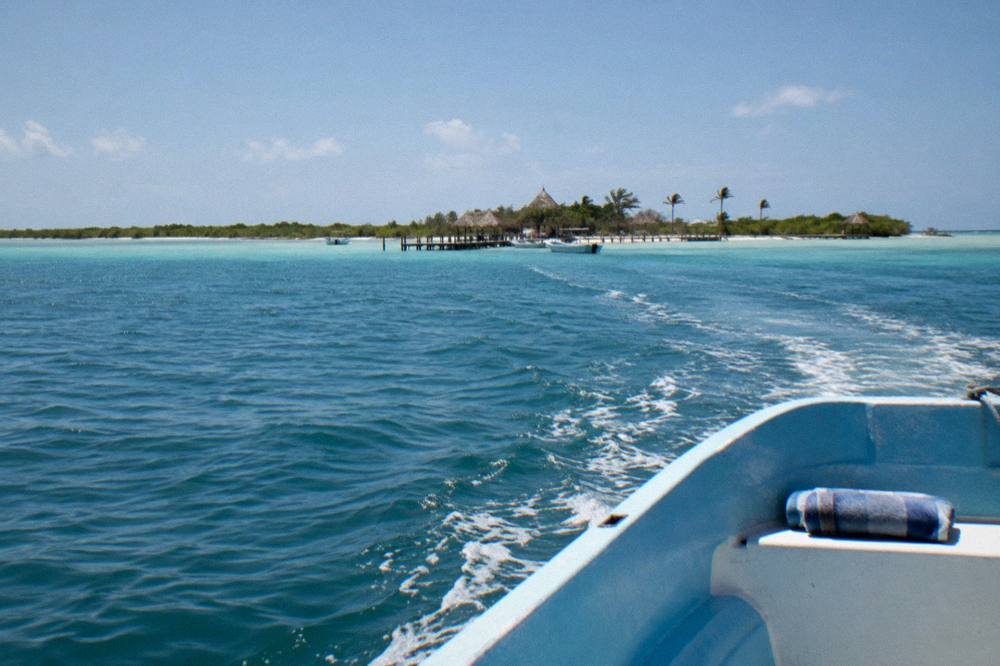 A single small boat on calm open sea under a bright midday sky