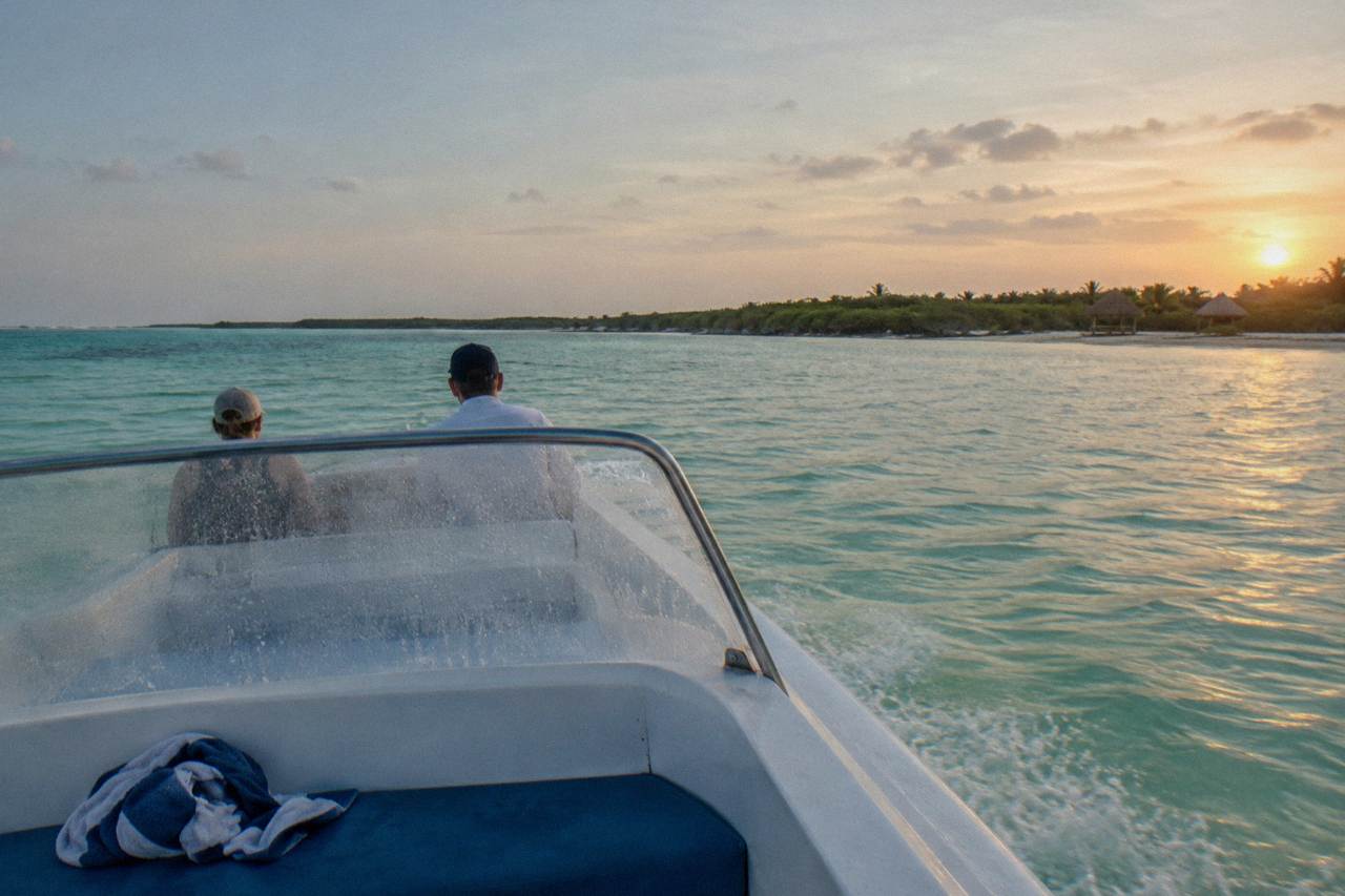 A small boat crossing open turquoise water at sunrise off the Yucatan coast