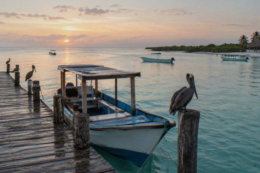 Wooden tour boat moored at a small dock on Holbox in early morning light