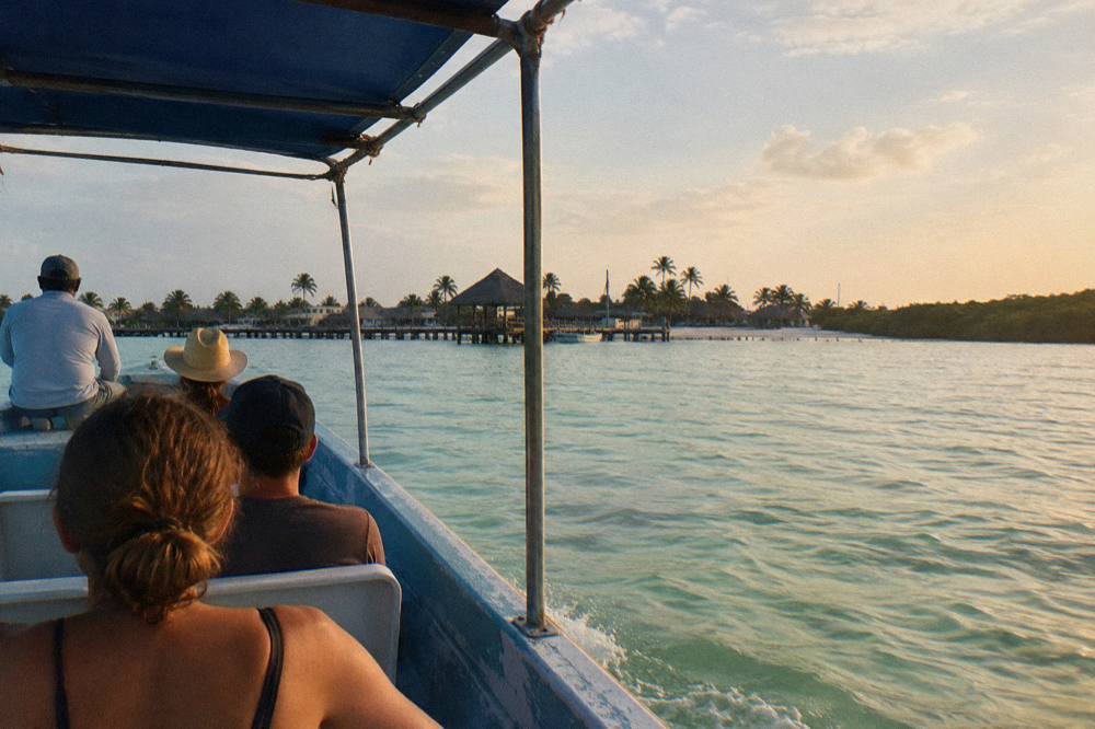 Tour boat returning toward Holbox shoreline in late afternoon light