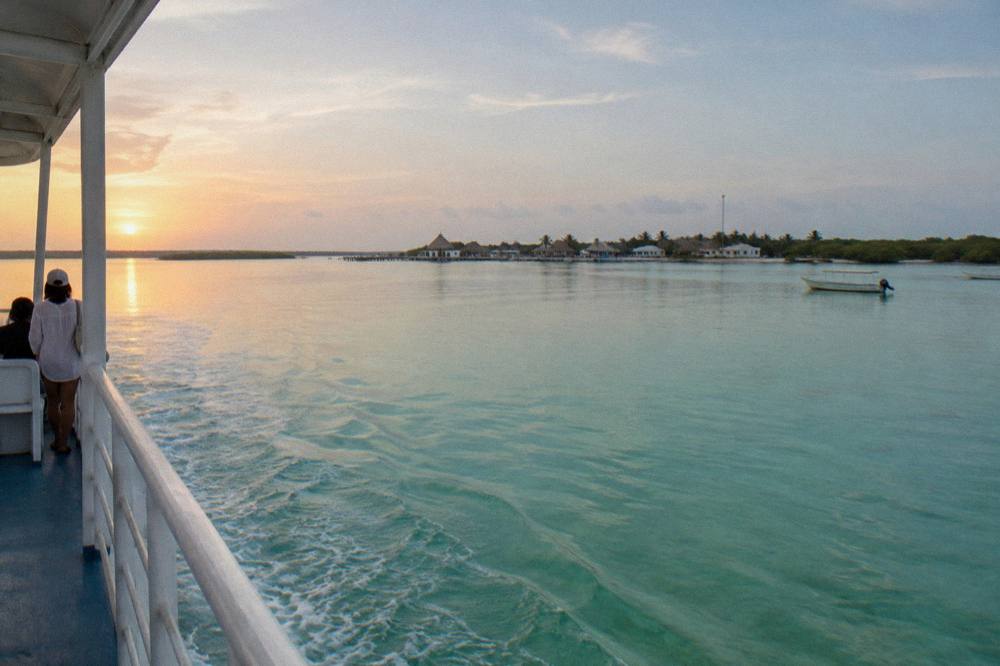 Ferry boat crossing calm shallow lagoon water toward a small island